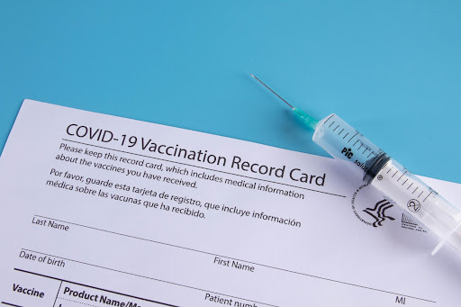 A syringe with a record card for COVID-19 vaccination. Image courtesy of https://www.flickr.com/photos/30478819@N08/51007959558